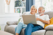 Couple Senior Using Computer Laptop On Sofa At Home For Online Shopping, Surfing Internet