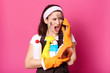 © sementsova321 - Image of screaming woman speaking on mobile phone while cleaning at home, dressed t shirt, apron and hairband, brunette lady holding sponge and detergents, model posing isolated over pink background.
