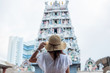 Woman traveling with white dress and hat, happy Asian traveler looking to Sri Mariamman Temple in Chinatown of Singapore. landmark and popular for tourist attractions. Southeast Asia Travel concept