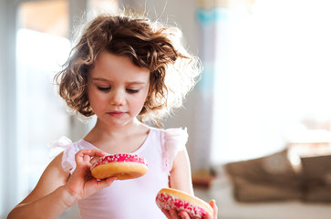 Wall Mural - A small girl with doughnuts at home.
