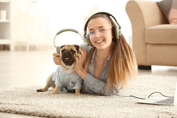 Canvas Print - Teenage girl with cute pug dog listening to music at home