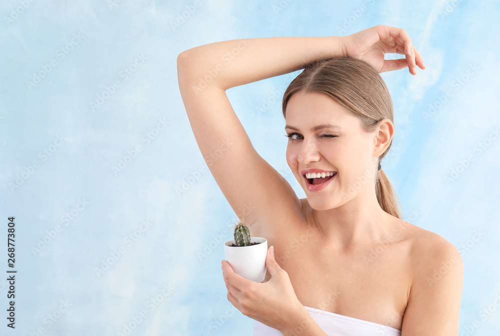 Beautiful young woman with cactus on light background. Depilation concept