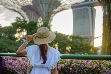 Fototapete - Young Woman traveling with white dress and hat, Asian traveler looking to supertree at gardens by the bay in Singapore. landmark and popular for tourist attractions. Southeast Asia Travel concept