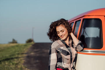 Wall Mural - A young girl on a roadtrip through countryside, standing by a minivan.