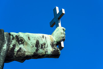 holy christian cross in copper rust covered hand isolated on blue sky background - concept christian