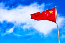 Waving Red National Flag Of China Against Blue Sky Background.
