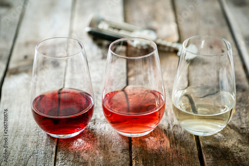 Fotomural WIne tasting concept - red, rose and white wine in glasses on wood background