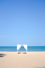 Beautiful romantic wedding dinner on the white sand beach with cloudless blue sunny sky in summer