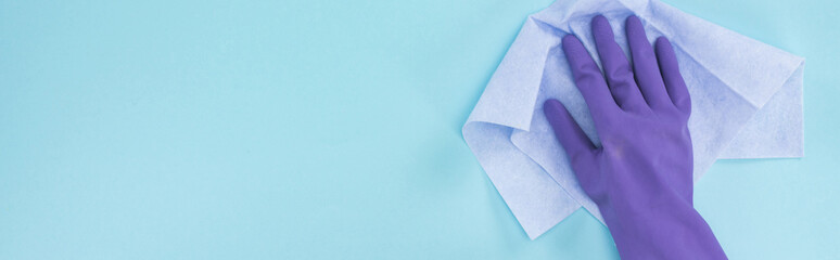 panoramic shot of cleaner in purple rubber glove holding rag on blue background