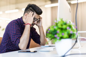 tired and worried indian business man at workplace in office