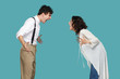 © khosrork - Profile side view portrait of two aggressive brunette partner standing and screaming at each other. conflict between to friend, partners or family. indoor studio shot isolated on blue background.