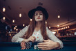 © RomanR - Woman in hat with playing cards and poker chips in casino