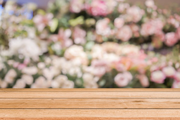 abstract blur beautiful flowers and floral background in beauty shop with brown wooden tabletop texture perspective counter for promote and show and advertise product on display	