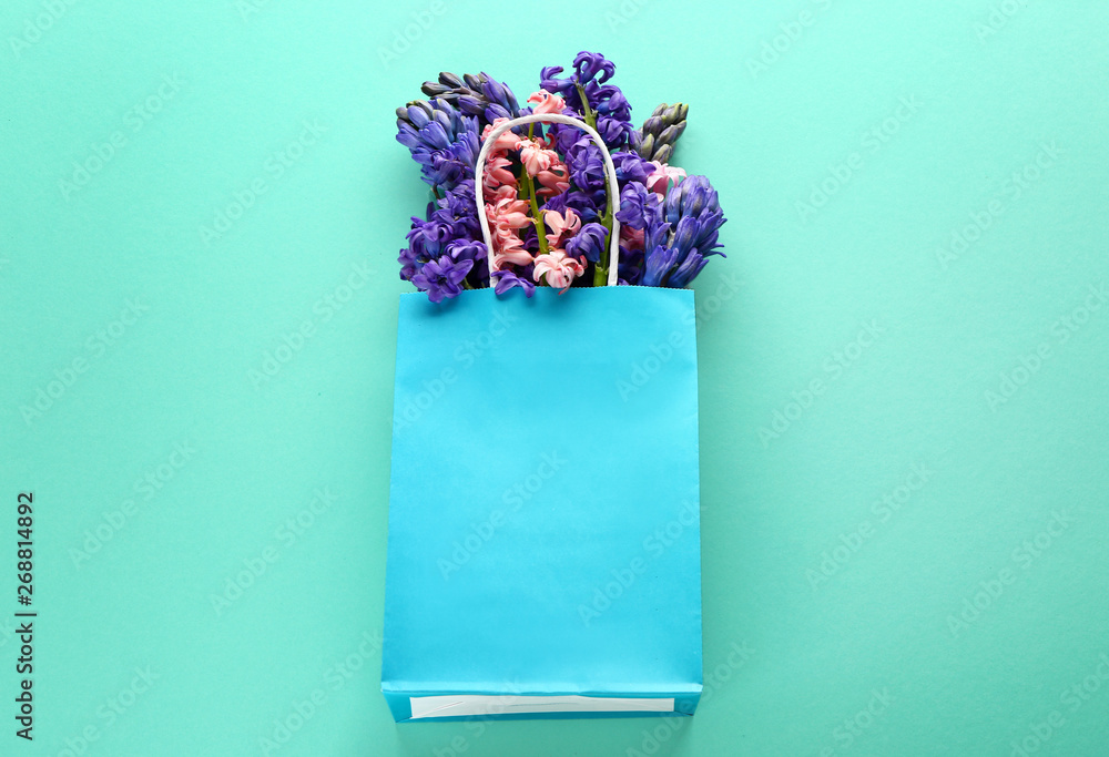 Bag with beautiful hyacinth flowers on color background