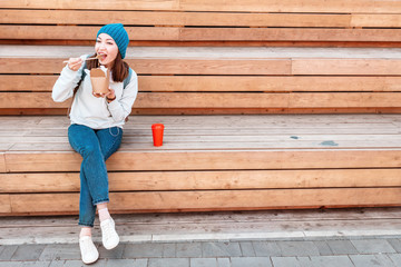 Wall Mural - Fashionable asian teen hipster girl eats Oriental wok noodles with chopsticks. Concept of lunch and natural takeaway containers made of paper