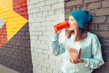 happy fashionable asian woman drinking coffee and eating wok noodles at the city street. Takeaway fastfood delivery concept