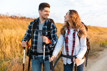 cheerful young couple carrying backpacks hiking together