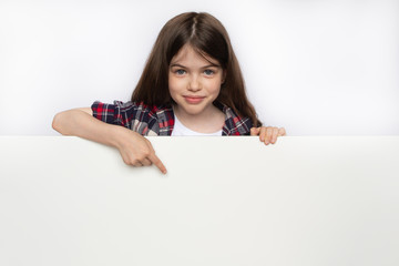 little cute girl points to an blank white board, space for text advertising, educational, advertising concept