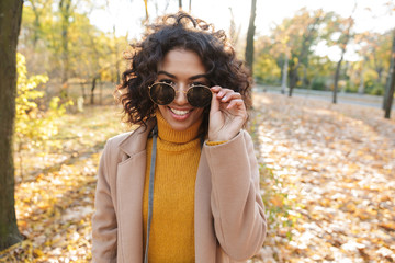 Smiling young african woman wearing autumn coat walking