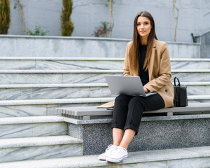 Sticker - Beautiful young woman wearing autumn coat using laptop