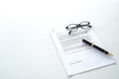 © Supagrit Ninkaesorn - White table with paper contract detail and empty space to sign authorized signature, props with glasses and ink pen, copy space on the left