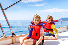 Two Little Kid Boys, Best Friends Enjoying Sailing Boat Trip. Family Vacations On Ocean Or Sea On Sunny Day. Children Smiling. Brothers, Schoolchilden, Siblings Having Fun On Yacht.