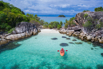 aerial drone view of man kayaking in crystal clear lagoon sea water during summer day near koh kra i