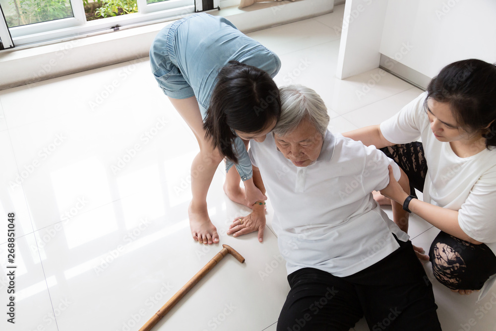 Asian elderly woman with walking stick on floor after falling down and caring woman assistant,sick senior or mother dizziness,faint,having a daughter,granddaughter to help and take care of her - obrazy, fototapety, plakaty 