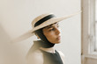 © Nicole Mason/Stocksy - dreamy portrait of woman wearing large straw hat with gold light leak