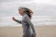 © Bonninstudio/Stocksy - Active senior woman walking on the beach in winter.