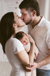 © Lea Csontos/Stocksy - New mother and father holding their baby and kissing