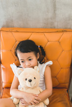 Asian Kid With Her Teddy Bear On The Old Chair
