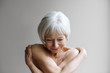 © Rob and Julia Campbell/Stocksy - Portrait of naked senior woman against gray background