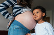 © Santi Nunez/Stocksy - Beautiful  girl listening pregnant mother's belly.