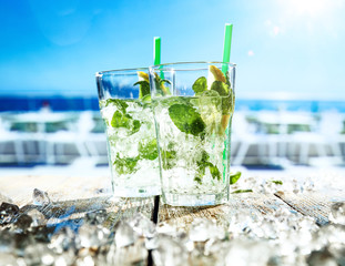 Fresh cold mojito drink on desk and beach bar background. 