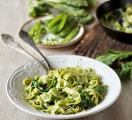 Wall Mural - green fettuccine pasta with spinach leaves and green peas. ready meals, vegetarian cuisine. Italian food. square format