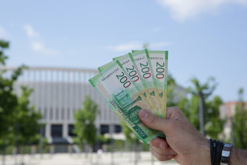 Male hand holds a new Russian banknote two hundred rubles on the background of a building and blue sky. Cash paper money