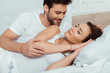 © LIGHTFIELD STUDIOS - happy man looking at attractive girl lying on bed with closed eyes