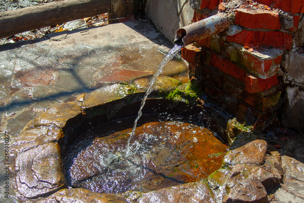 Natural spring folded of old bricks and metallic pipe. Clean fresh ...