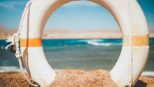 Closeup Image Of Beautiful Sea Beach And White Plastic Kife Saving Ring At Bright Sunny Day. Perfect Shot To Illustrate Summer Holiday Vacation At Ocean.