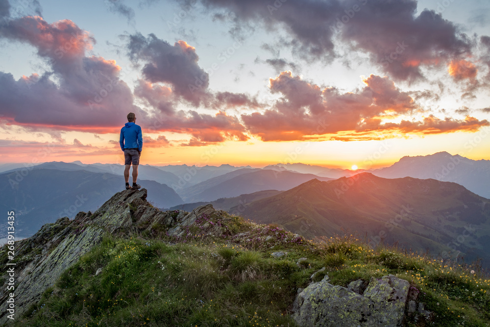 Man watching dramatic sunset in the mountains - obrazy, fototapety, plakaty 
