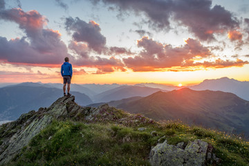 man watching dramatic sunset in the mountains