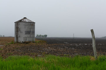 Single metal silo on open field as the Spring rain falls.