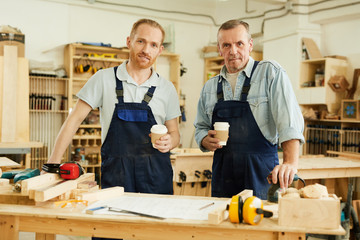 Waist up portrait of two carpenters looking at camera while standing in joinery workshop, copy space