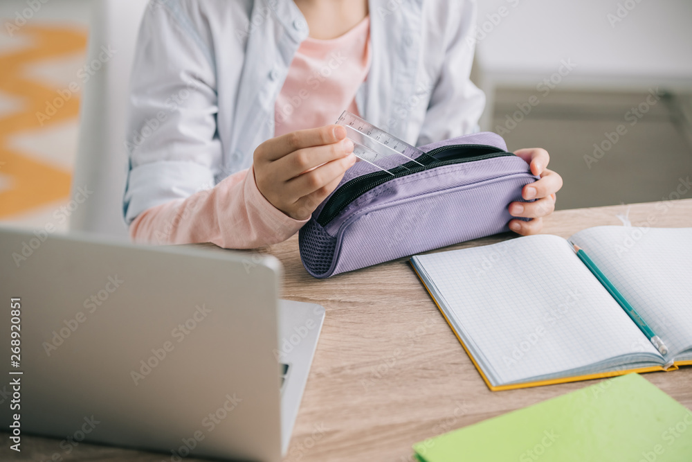 cropped view of child getting ruler out of pencil case while doing ...