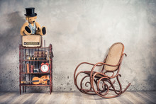 Teddy Bear In Cylinder Hat On Vintage Radio, Antique Books, Clock, Camera, Binoculars, Fiddle, Keys On Shelf, Aged Rocking Chair Front Concrete Wall Background. Retro Old Style Filtered Photo 
