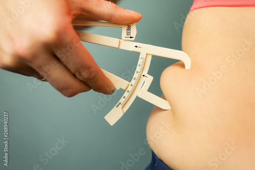 Fotografía Woman measuring her body fat with caliper