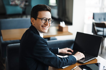 side view portrait of a stylish adult caucasian manager wearing suit and glasses looking at camera s