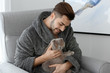 © Pixel-Shot - Young man with cute funny cat at home