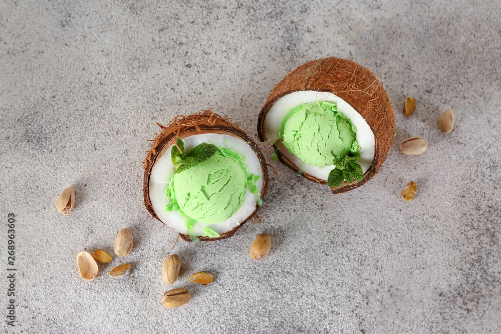 Fresh coconut with tasty ice cream on grey background